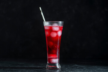 Fresh red cherry cocktail with ice cubes in glass on black background. Summer iced refreshing drink