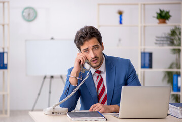 Handcuffed young male employee sitting in the office