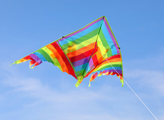 colorful kite with many colors flying high in the blue sky