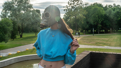 Girl in a gas mask in the rays of the sun. Alienation in the city. Fashion, ecology and loneliness...