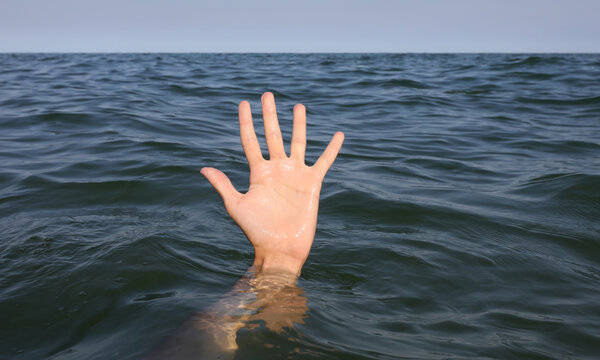 Large Open Hand With Five Fingers Emerging From The Surface Of The Sea Of A Person About To Drown Under Water