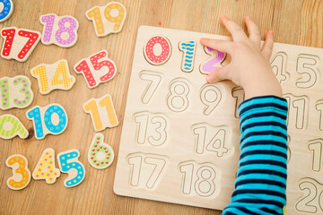 Kid learning numbers through game. Activity with wooden numbers. Educations at home, pre-school...