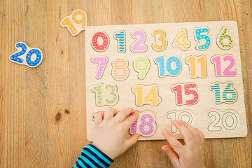 Kid learning numbers through game. Activity with wooden numbers. Educations at home, pre-school education, Montessori methodology. Toy to learn counting and stimulate imagination, creativity