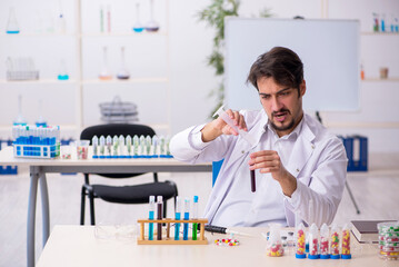 Young male chemist in drugs synthesis concept