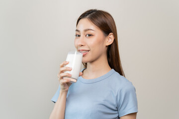 Asian young woman drinking a glass of milk isolated on background.