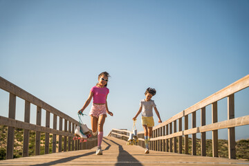 Two girls with roller skates at the hands running with happy faces