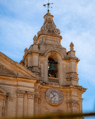 Medieval clock and bell tower. Midday, few clouds. Mdina, Malta.