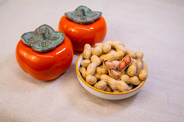 Persimmon-shaped decorations and peanuts are placed on the background,means Good things happen