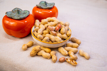Persimmon-shaped decorations and peanuts are placed on the background,means Good things happen