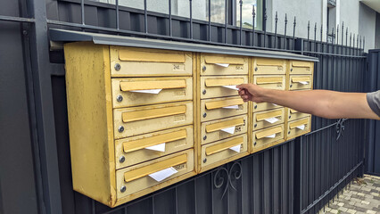 Yellow mail boxes full with letters and correspondence.  Man receiving utility bill in letterbox. Letter shipment delivery into old postal vaults.