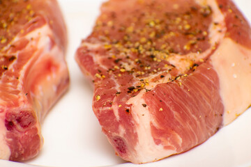 raw pork steak on a white plate