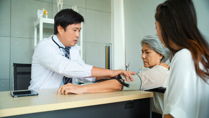 Male doctor measures the blood pressure of a senior female patient in the examination room.