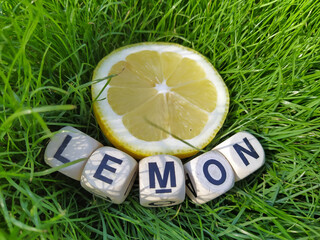a lemon cut in half lies on the green grass.  vitamin C