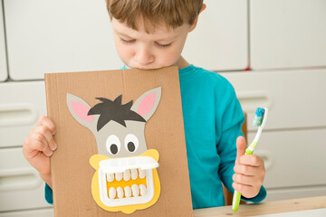 A dentist. Kid plays with DIY toy. Boy washing donkey teeth with toothbrush. Idea for smart mommy how to motivate children to brush your teeth? Wet wipes door mouth and bean teeth.