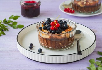 Cottage cheese casserole or soufflé with blueberry jam, fresh blueberries and red currants in portion molds on a purple wooden background.
