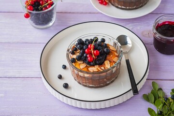Cottage cheese casserole or soufflé with blueberry jam, fresh blueberries and red currants in portion molds on a purple wooden background.