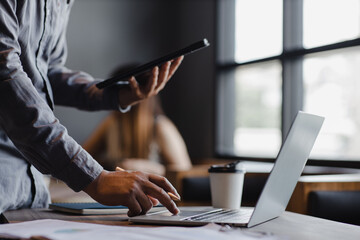 Close-up shot of business man working with laptop and tablet and online marketing and business concept graph.