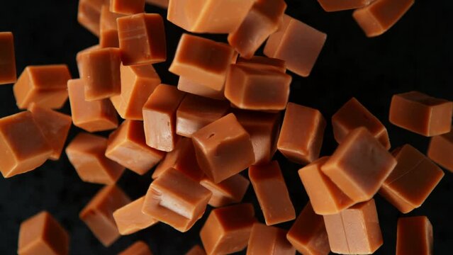 Super Slow Motion Shot of Caramel Pieces Exploded Towards Camera Isolated on Black at 1000fps.