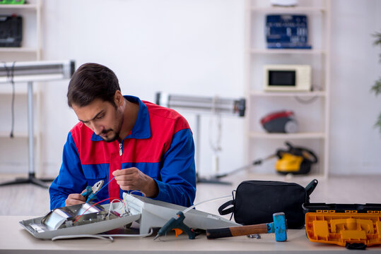 Young male repairman repairing heater