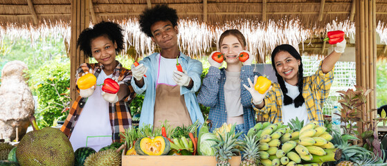 A happy teenager is standing and holding vegetables and fruits from the farm.