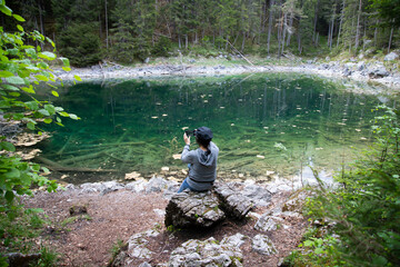 Obraz na płótnie Canvas Caucasian female sitting on a stone near the Eibsee Lake, Germany. Travel, lifestyle concept.
