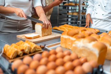 A female chef in a bakery carefully prepares fresh bread for the day's customers.