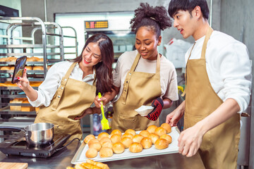 Students In Cookery Class Mixing Ingredients For Recipe In Kitchen.Group of young people taking...