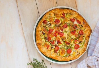 Open shortbread pie with zucchini, tomatoes, sweet peppers and mozzarella cheese on a ceramic plate...