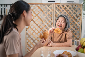 Asian senior mother having breakfast and talking with daughter at the tablet. Asia family enjoy eating together.