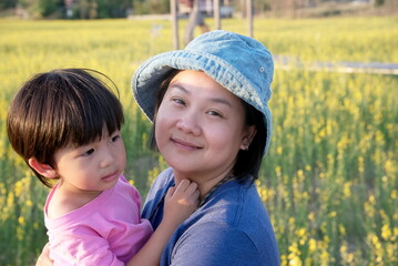 Young asian mother hugging her son and looking at camera