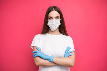 Young woman wearing protective mask on face and medical gloves keeping arms crossed. Confident girl, female doctor in medical mask and protective gloves.