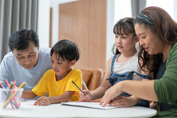 Asian parents teaching and helping kids to do homework at home, family spending time together. mother and father taking care of son and daughter. support knowledge and education