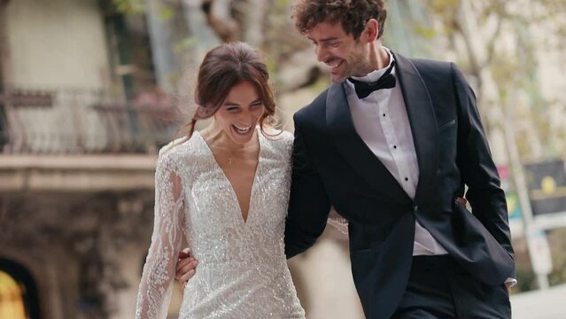 Young Couple Bride And Groom Walking Down Street Holding Hands.
