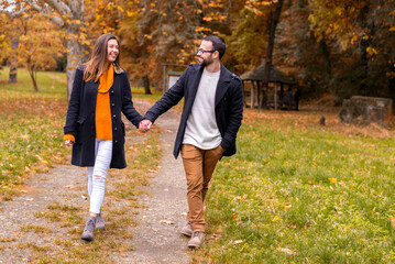 Fototapeta premium Smiling young couple in love having fun in the park on a beautiful autumn day