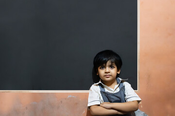 Indian school girl standing against black board in classroom