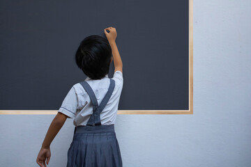 Indian school girl writing on black board, rear view