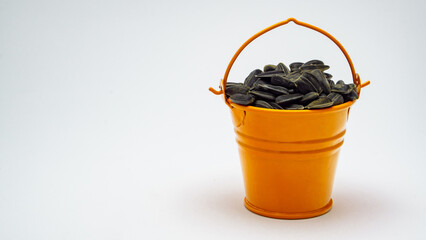 sunflower seeds in an orange bucket on a white background