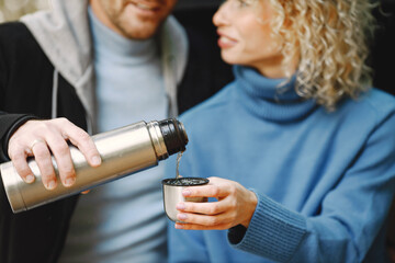 Cropped photo of a thermo cup in hands of couple