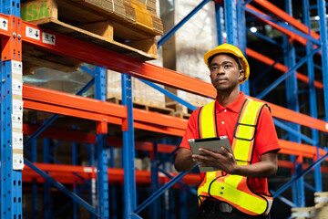 A man in charge of a large warehouse is checking the number of items in the warehouse that he is responsible for. By tablet