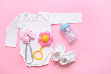 Obraz na płótnie Canvas bodysuit, rattle, booties, bottle, pink bow for a newborn on a pink background