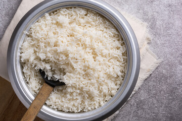 pot of cooked white basmati rice with a wooden spoon, just cooked long grained aromatic rice on a table top, taken from above with space for text