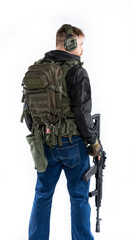 airsoft player in full growth. a man in an outfit, in headphones, a bulletproof vest, with a rifle and a pistol on a white background. standing with his back to us
