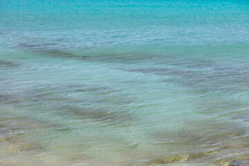 Sea cloudy shallow water turquoise blue color background. Overhead view of rocky and plant bottom.