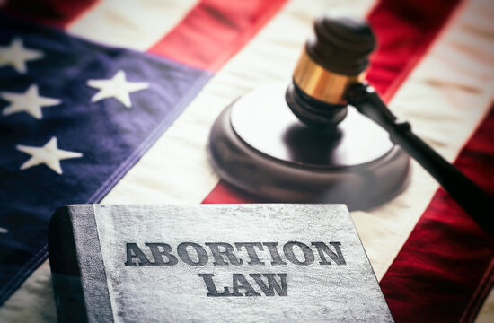Abortion law in USA concept. Pregnancy termination ban. Judge gavel and Abortion Law book on US flag