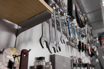 Rack with wrenches of different sizes and other tools close-up in the repair shop. Professional...