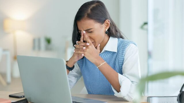 One student with burnout looking unhappy while trying to meet a deadline for a task. Young female intern suffering from a headache while typing an email on a laptop in an office alone at work