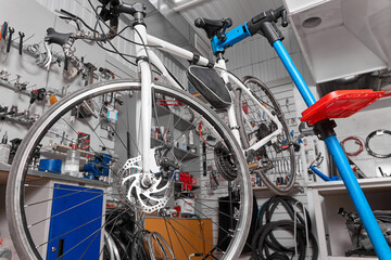 White bicycle is fixed on a blue holder for preventive inspection and repair in the service center....