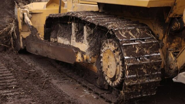 Construction machinery equipment, earth building bulldozer, earthmoving machine technology, industrial erection concept. Bulldozer working on mud at a construction site. Close up