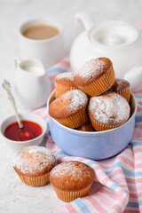 Homemade muffins with tea, teapot, cream and jam on the table