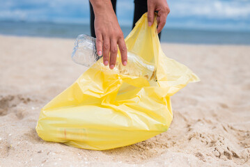 girl collects plastic bottles with garbage on the beach to save the cleanliness of the planet and ecology